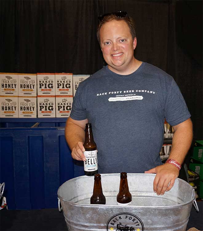Rep from Back Forty Brewing poses with bottle of favorite beer