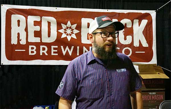 Red Brick Brewing Rep talks with Porch Drinking staffer in front of brewery banner