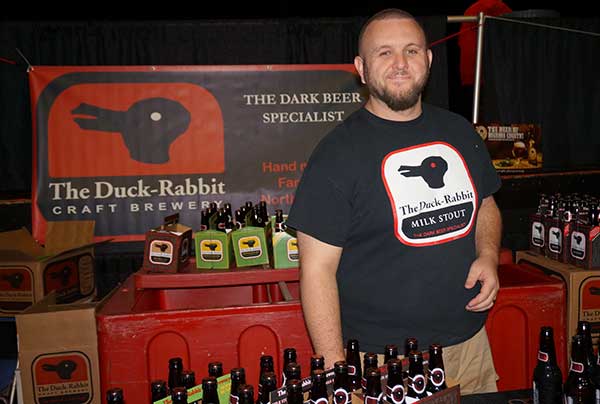Duck Rabbit Brewing Rep poses while surrounded by bottles of Duck Rabbit beer