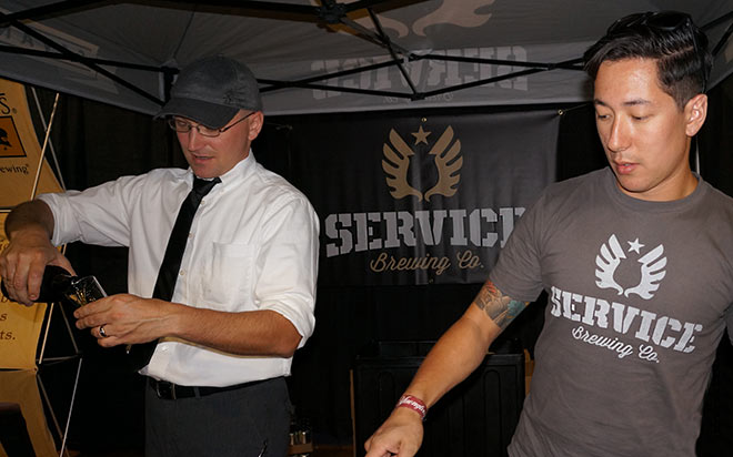 Service Brewing rep points out beer to festival attendee while partner pours samples