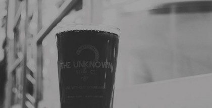 Black and white photo of a pint glass of beer in an industrial setting.