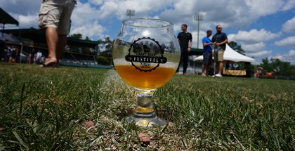 Augusta Beer Fest glass sitting on grass with a blue cloudy sky overhead