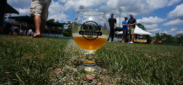 Augusta Beer Fest glass sitting on grass with a blue cloudy sky overhead