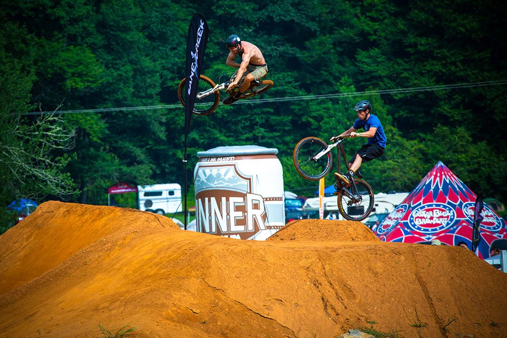 BMX bikes doing stunts on dirt ramps at Oskar Blues Burning Can NC