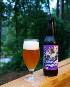 Unknown Brewing Co. Kitten Snuggles Imperial Farmhouse ale poured in a tulip glass next to the bottle