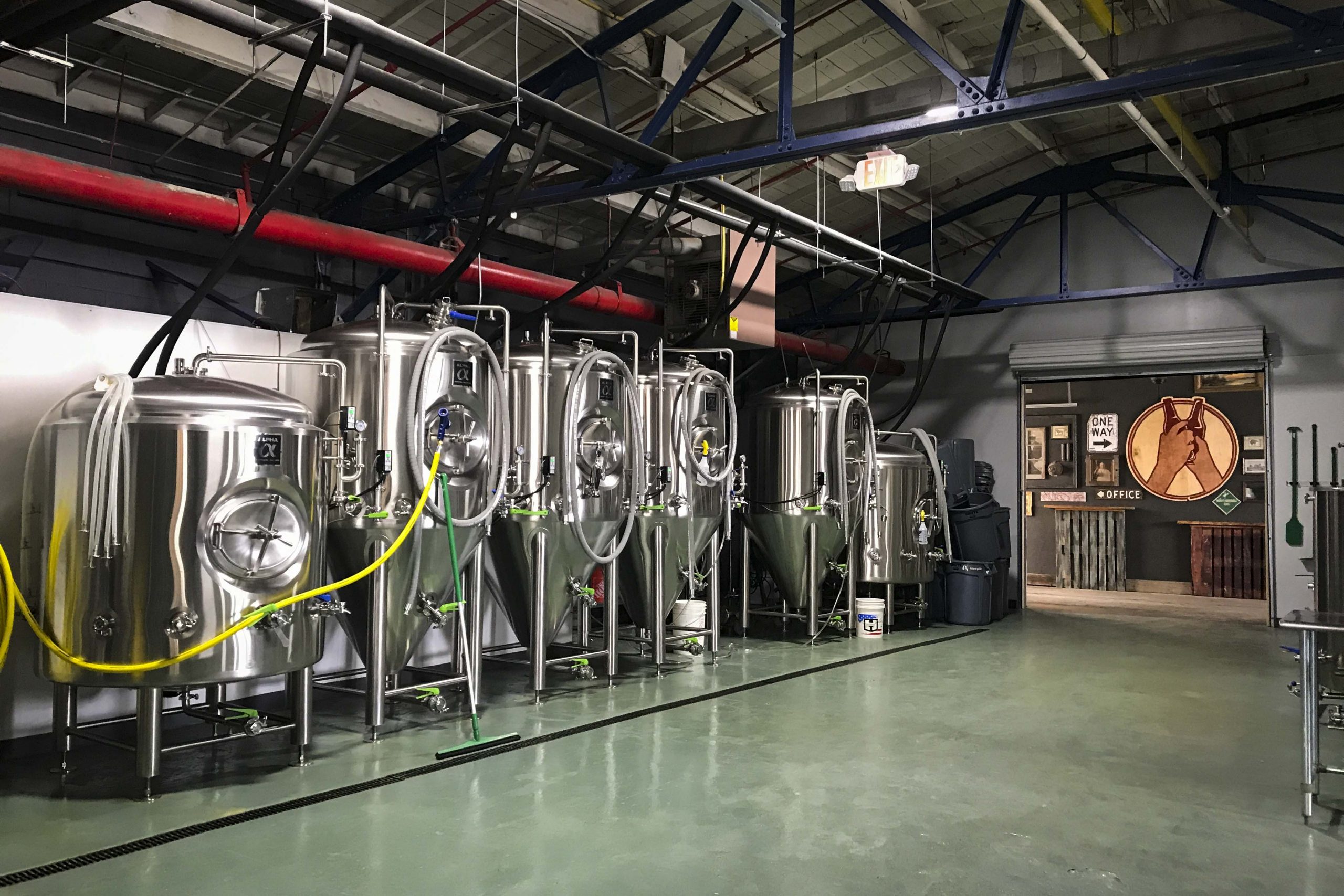 A group of stainless steel vessels shines in the light in Amorphic's brewery area