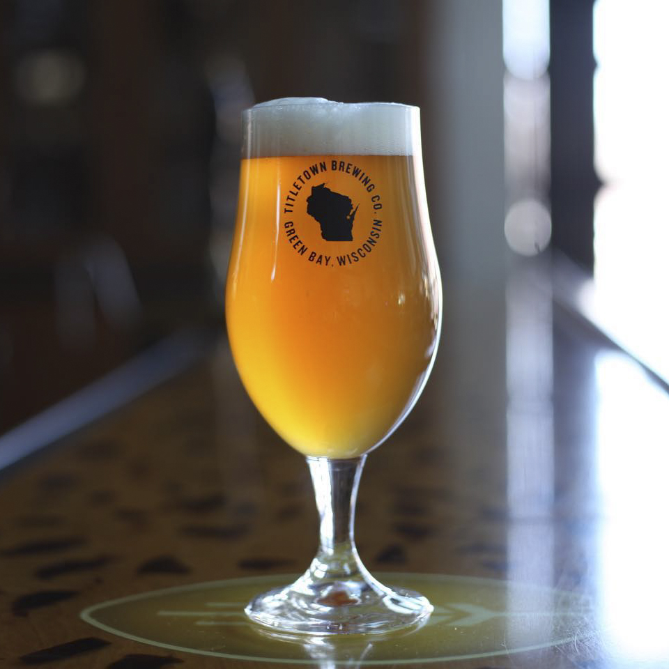 A backlit tulip glass of Octavia White IPA on the bar at Titletown Brewing Co.