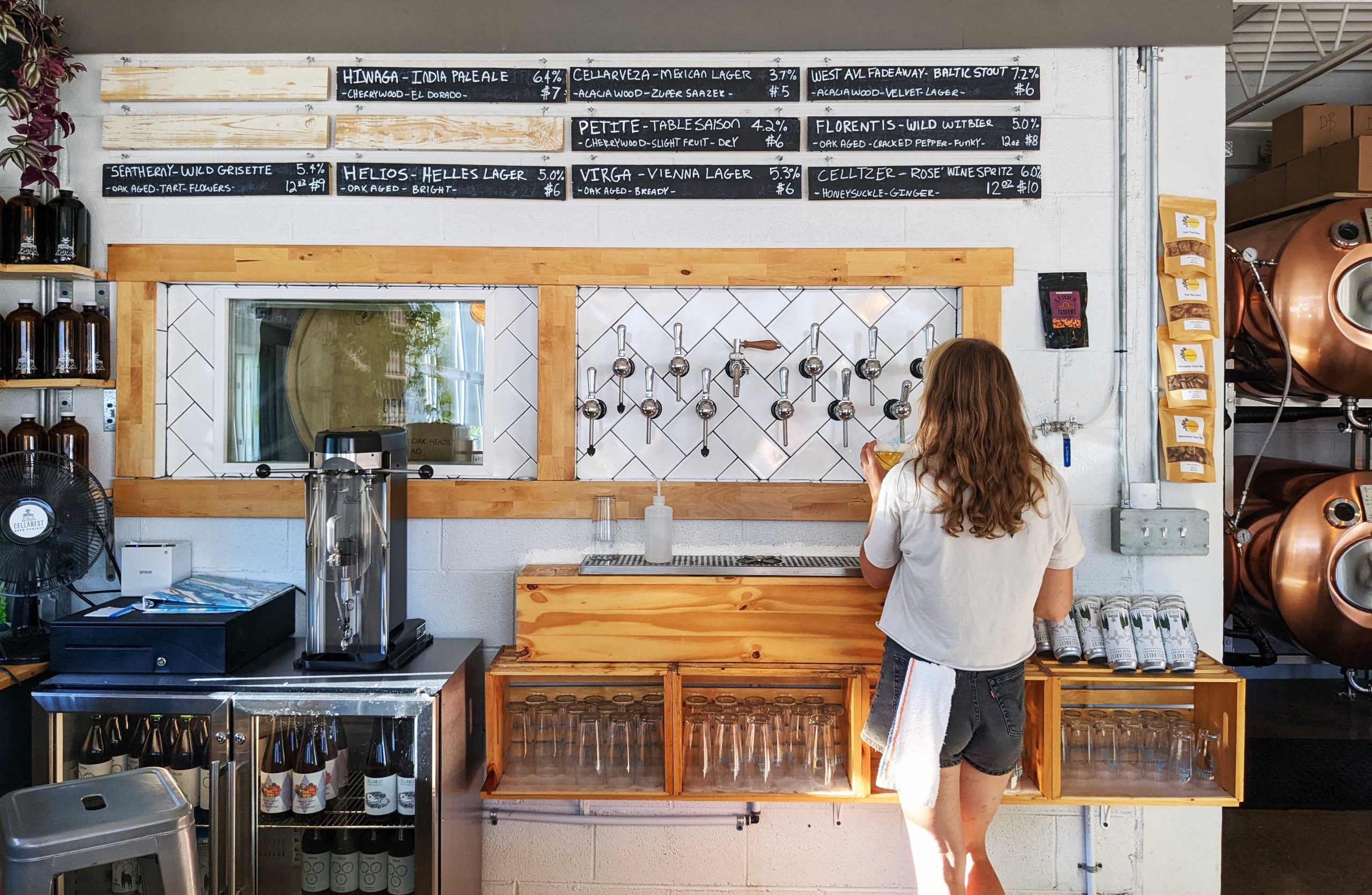 person pouring a pint behind the bar at a brewery