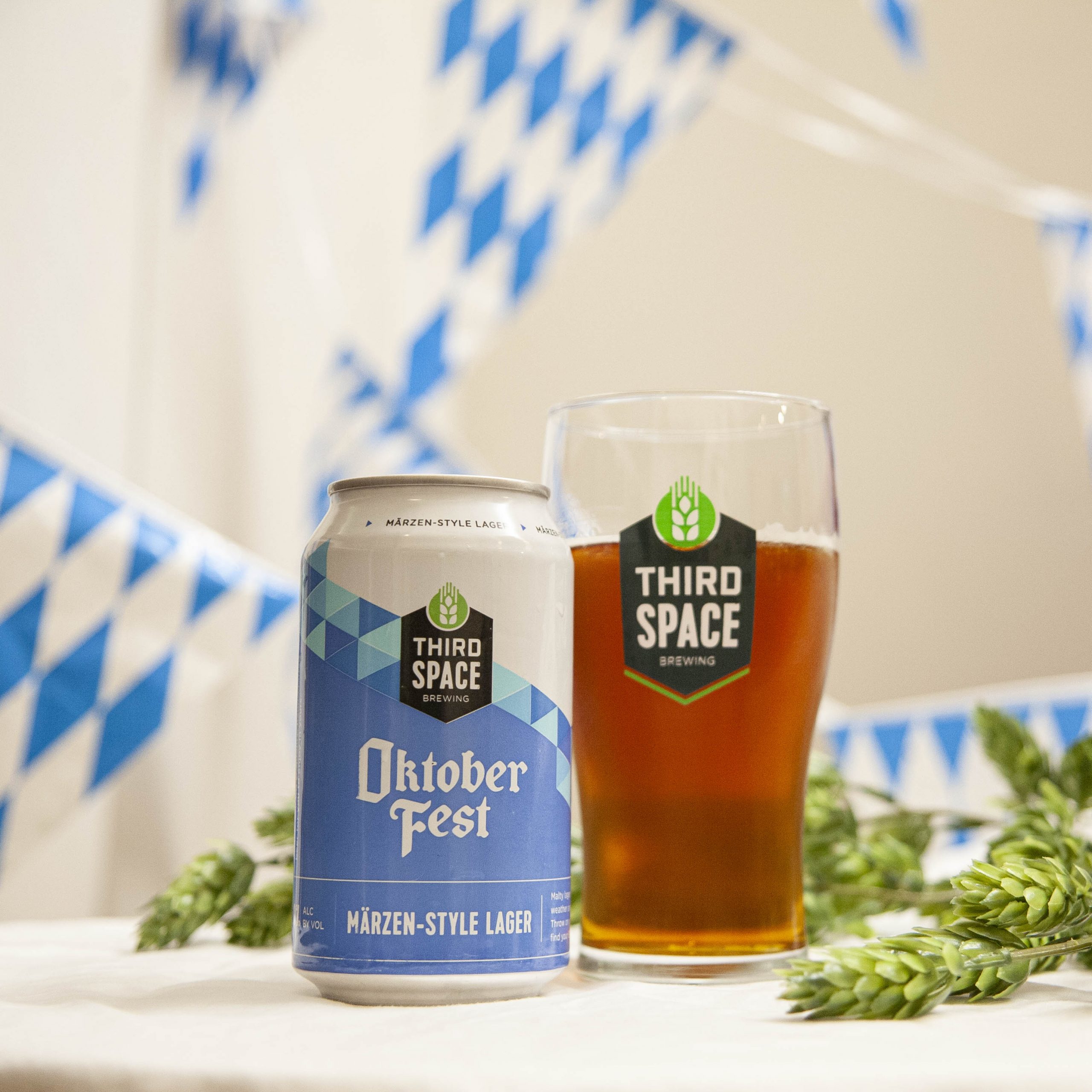 Third Space's Oktoberfest is poured into a branded glass, amidst hop cones and blue and white bunting. 