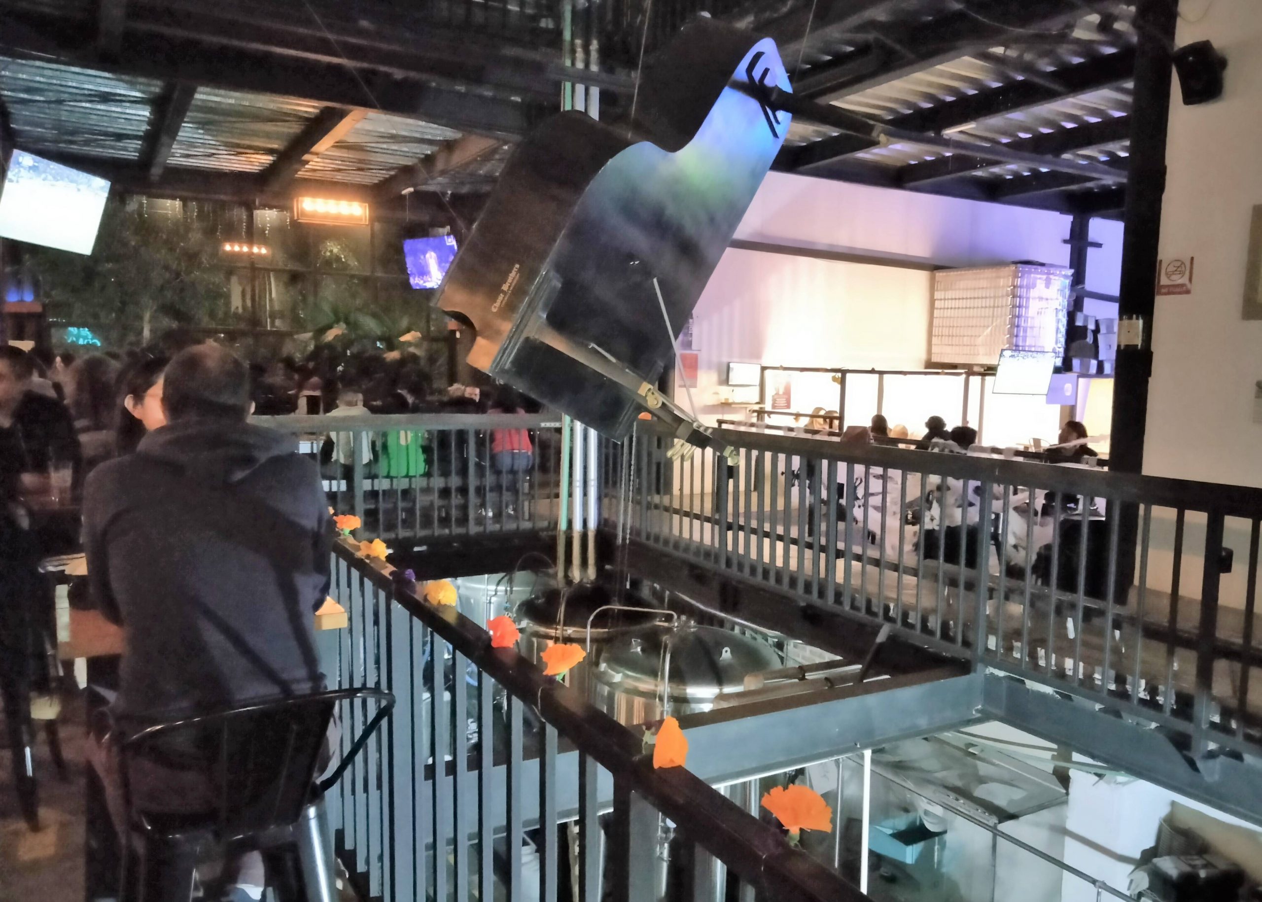 Patrons drink in a Mexico City taproom, where a piano is suspended from the ceiling.