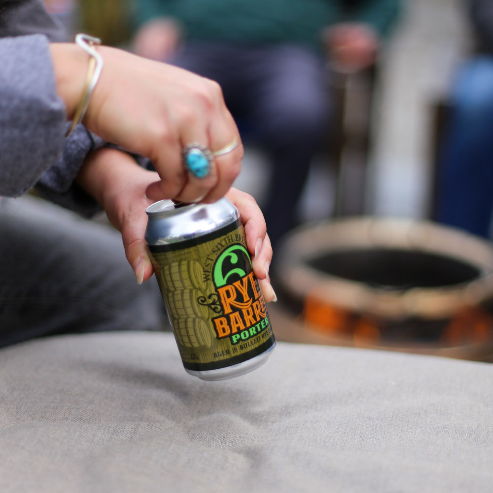 A person wearing a sterling silver bracelet and sterling-and-turquoise rings opens a can of West Sixth Brewing's Rye Barrel Porter.