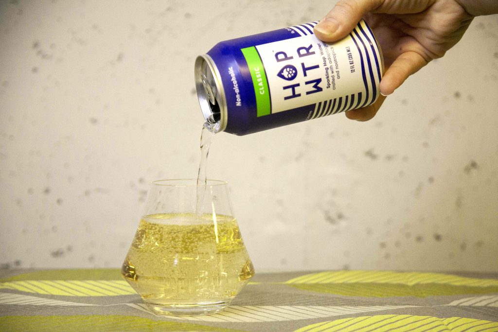 A can of adaptogen and nootropic infused HOP WTR is poured into a glass