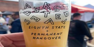 A photo of a commemorative glass from Altered States, about three-quarters full of beer.