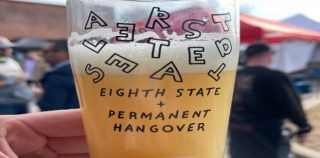 A photo of a commemorative glass from Altered States, about three-quarters full of beer.